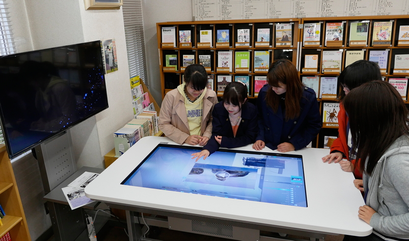 写真：図書館のディスカッションテーブルにモニターやタブレットと繋いでディスカッション