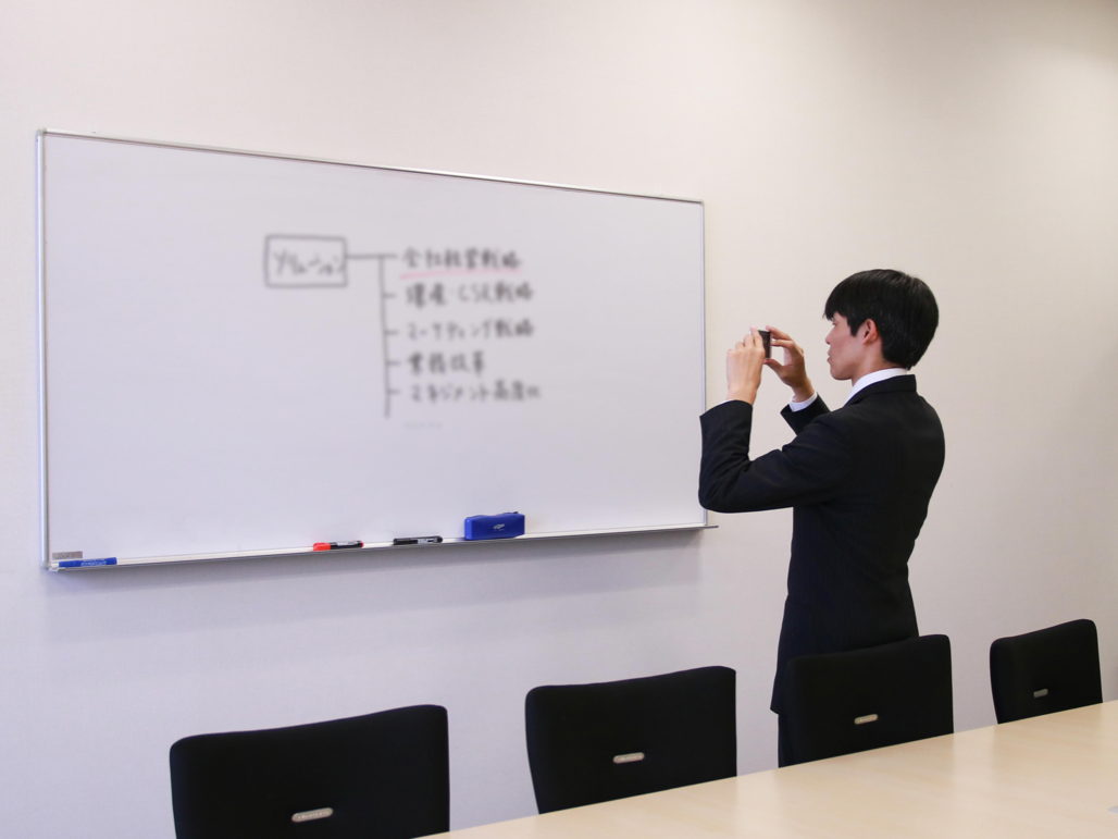 写真:ホワイトボードに書かれた内容を撮影する様子