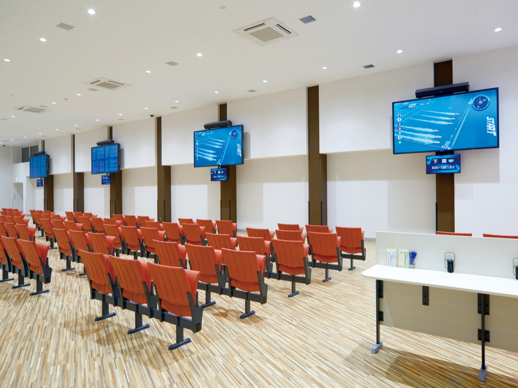 写真：一般席の壁面にTH-98LQ70Jを4台設置。1台につき1場分の情報を表示している