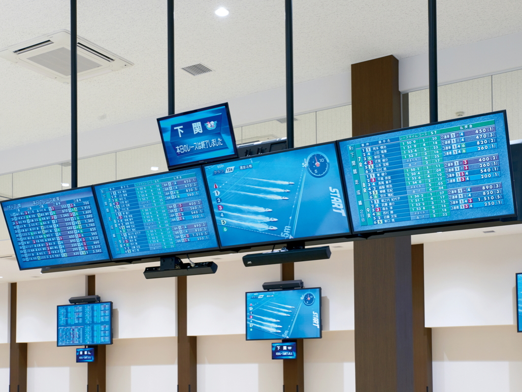 写真：会場中程にはTH-43LFE8Jが天井吊りにて設置されている。4台1セットで1場分の情報を表示。8セット導入されており、8場分の情報が網羅されている