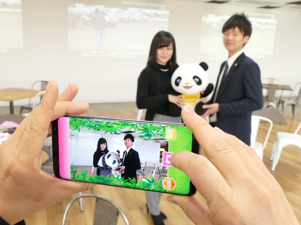 写真:ぬいぐるみを抱っこしてスマートホンでかざすと、シャンシャンの立体CG画像が画面に表示される