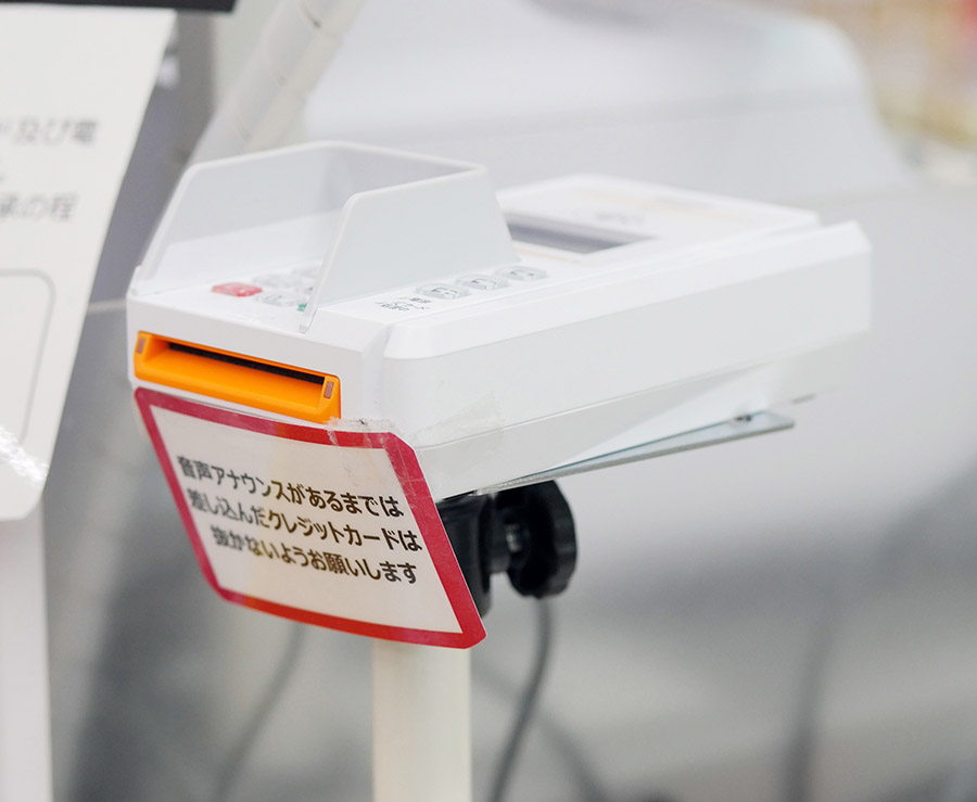 写真:キリン堂様店舗での基本的な設置スタイル。利用者の 目線で差し込み口が見えやすいよう少し斜めにした台に乗せて運用。JT-R600CRが軽量であり裏面に固定用のネジ穴があるため、台上でもしっかり安定