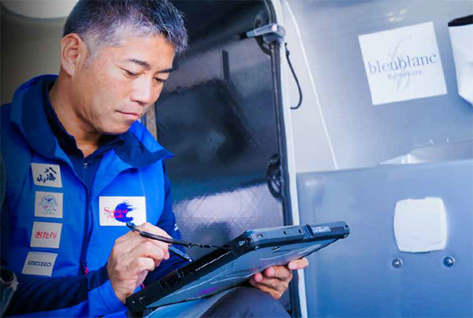 写真:タブレット部分を取り外し甲板で作業をする白石さん