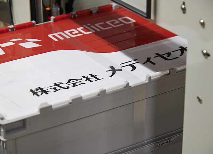 写真:梱包用テープで自動バンドルした専用の配送ボックス。「完全梱包」で高精度を確保したまま、お客様のもとへ届けられる