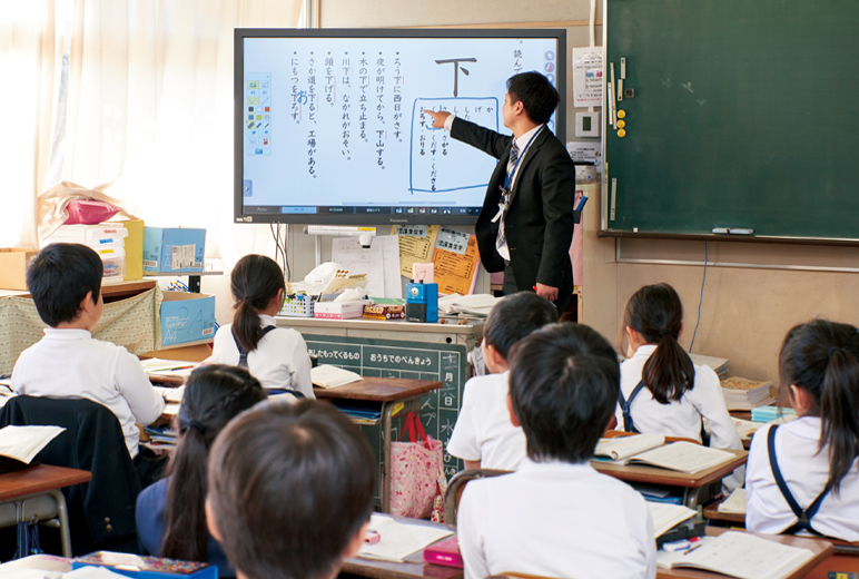 写真:国語の授業中の様子。タッチスクリーンディスプレイに映し出された教材に書き込む教諭。