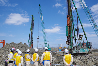 写真:杭基礎工事の現場。作業している人々の様子。