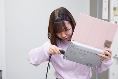 写真:学生がレッツノート側面にVGA端子を接続しようとしている様子。