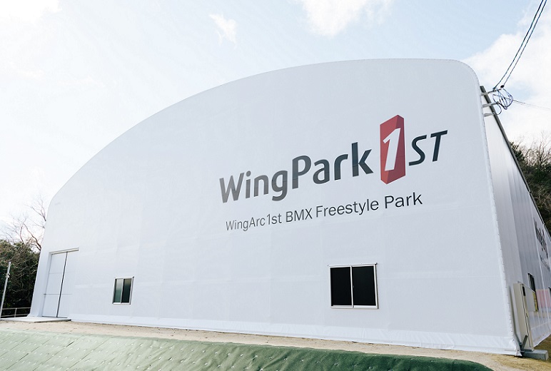 写真:WingPark1st 外観の様子。白いドーム型の建物の壁面に大きく「WingPark1st」のロゴが描かれている。