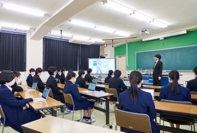 写真:巨大な電子黒板と、一人一台のレッツノートを用いて授業が行われています。