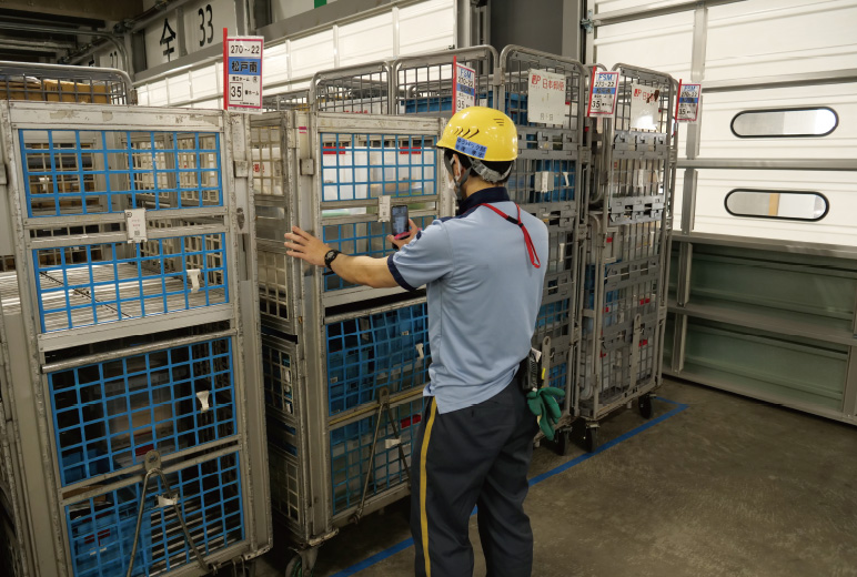 写真：局員がパレットをバースに並べ、宛先や内容品情報の入った二次元コードを読み込み