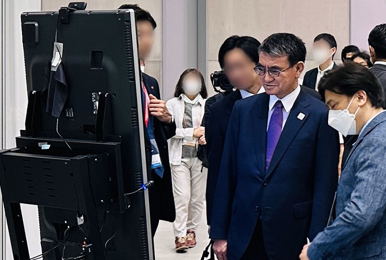 河野大臣にパナソニックブースの展示説明を行う