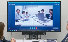 写真:液晶ディスプレイに映った人々とビデオ会議をしている様子。